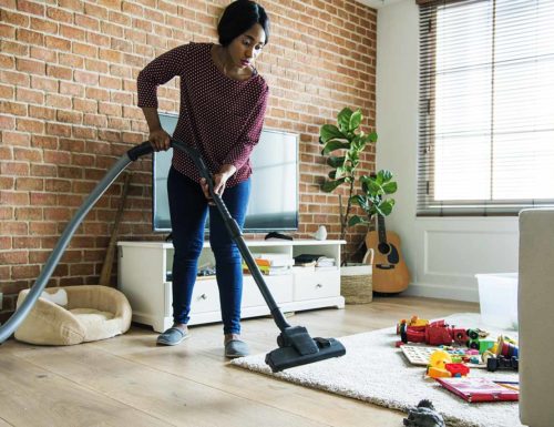 aide ménagère noire nettoie la maison avec un aspirateur