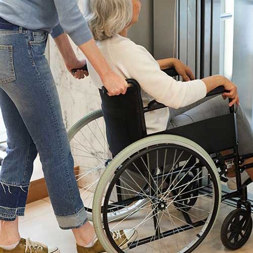 aide soignante pousse une femme âgée en chaise roulante